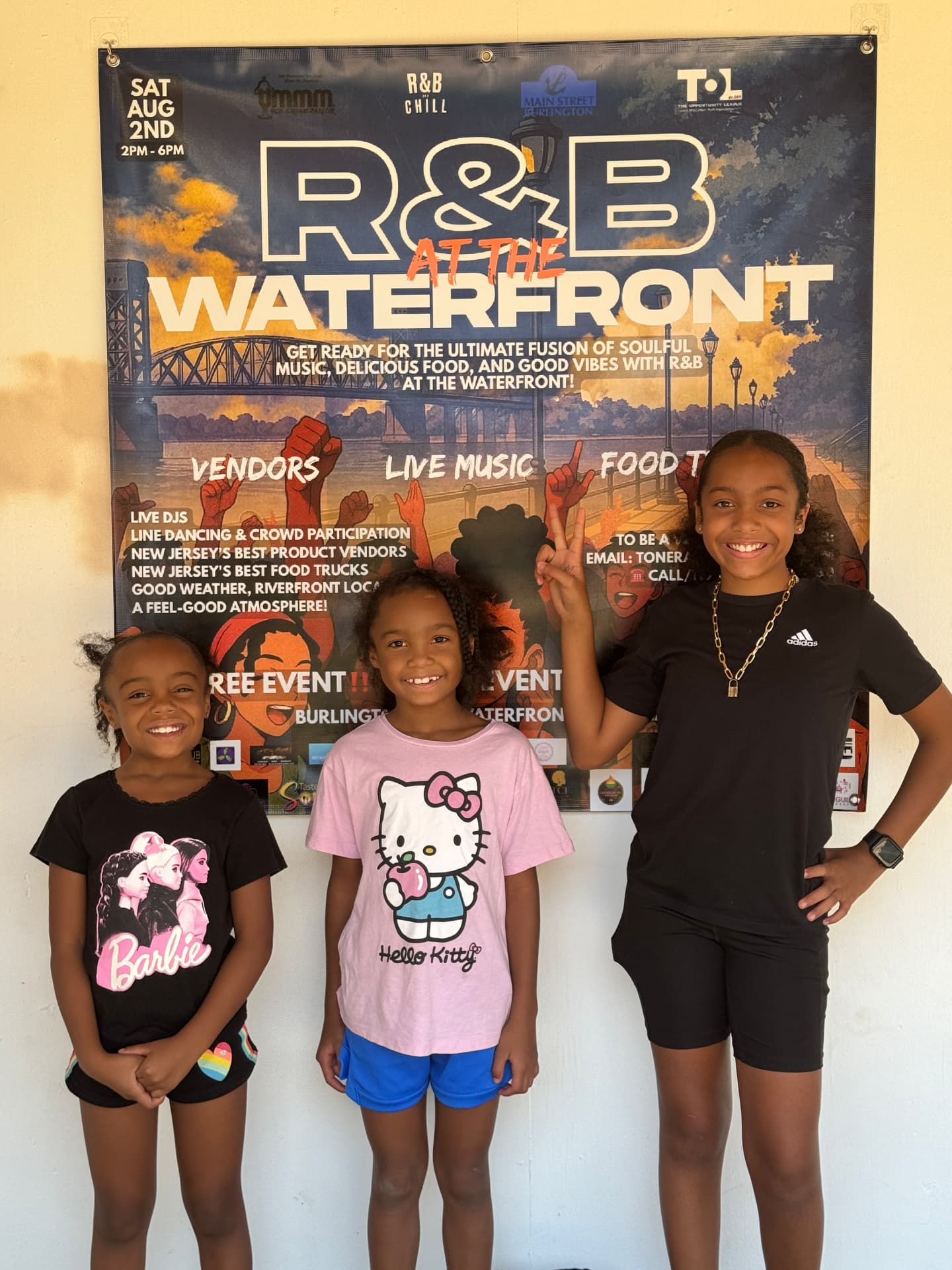 Three young participants in front of the R&B at the Waterfront banner